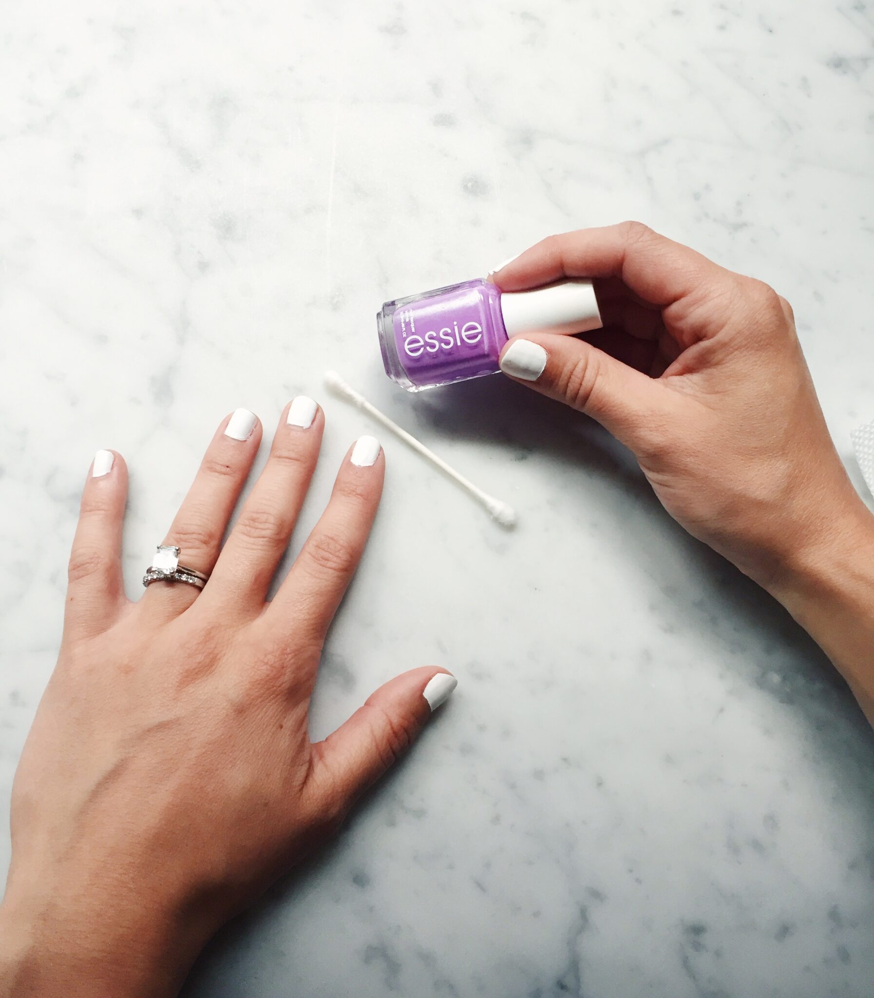 white base nail polish with essie purple nail polish and a q tip