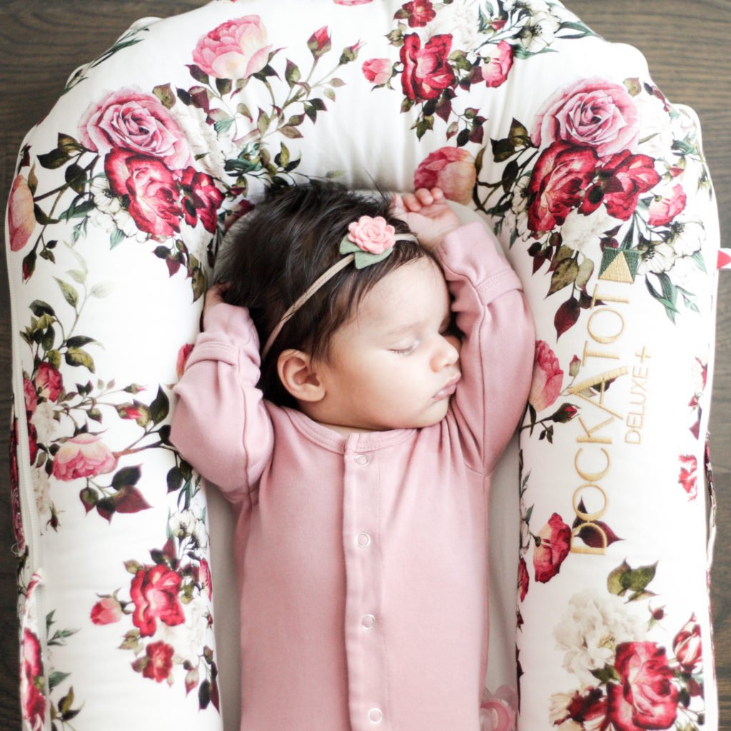 Newborn baby girl sleeping in a floral dockatot deluxe.