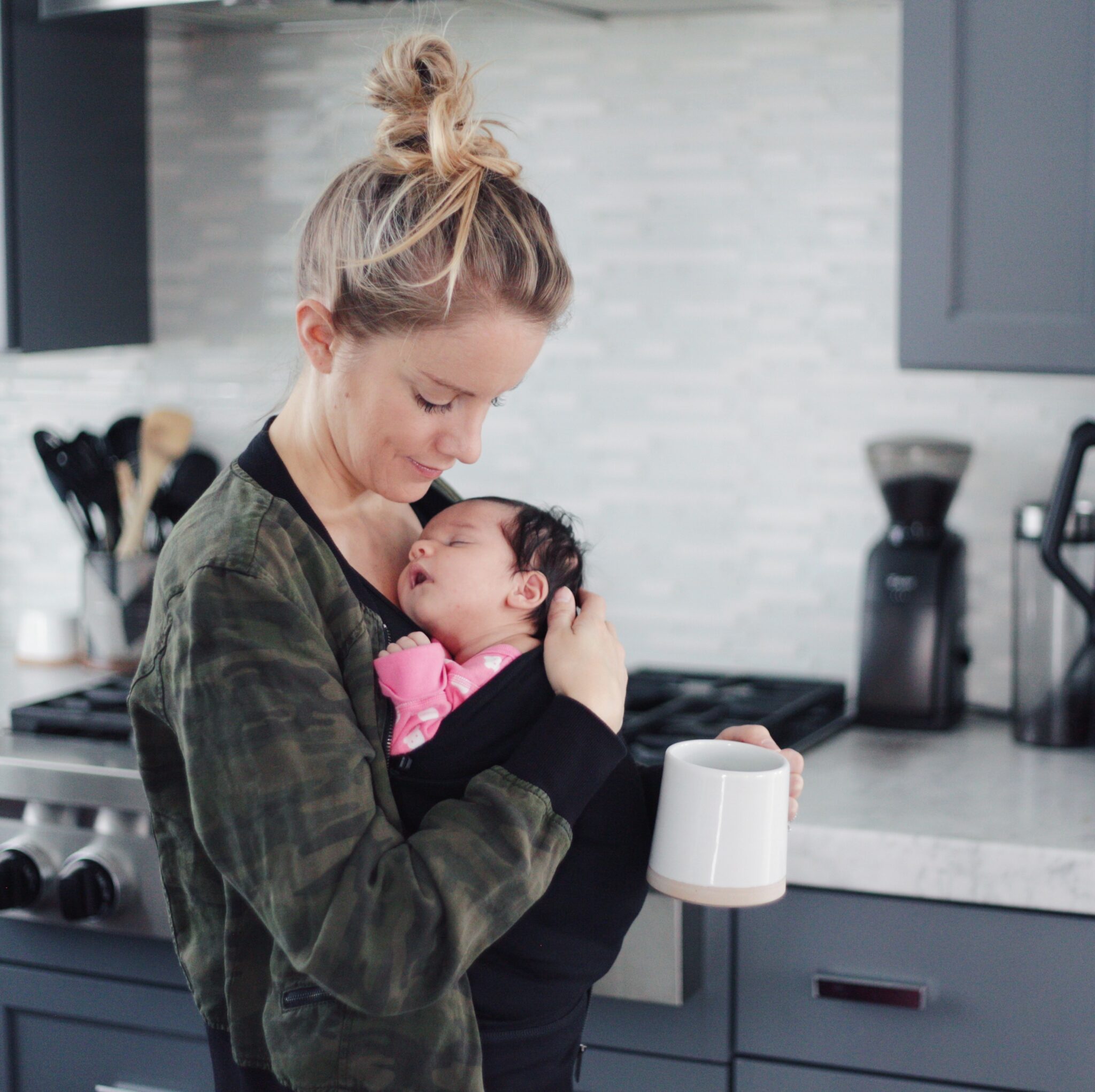 a mom carrying a newborn in a lalabu soothe shirt