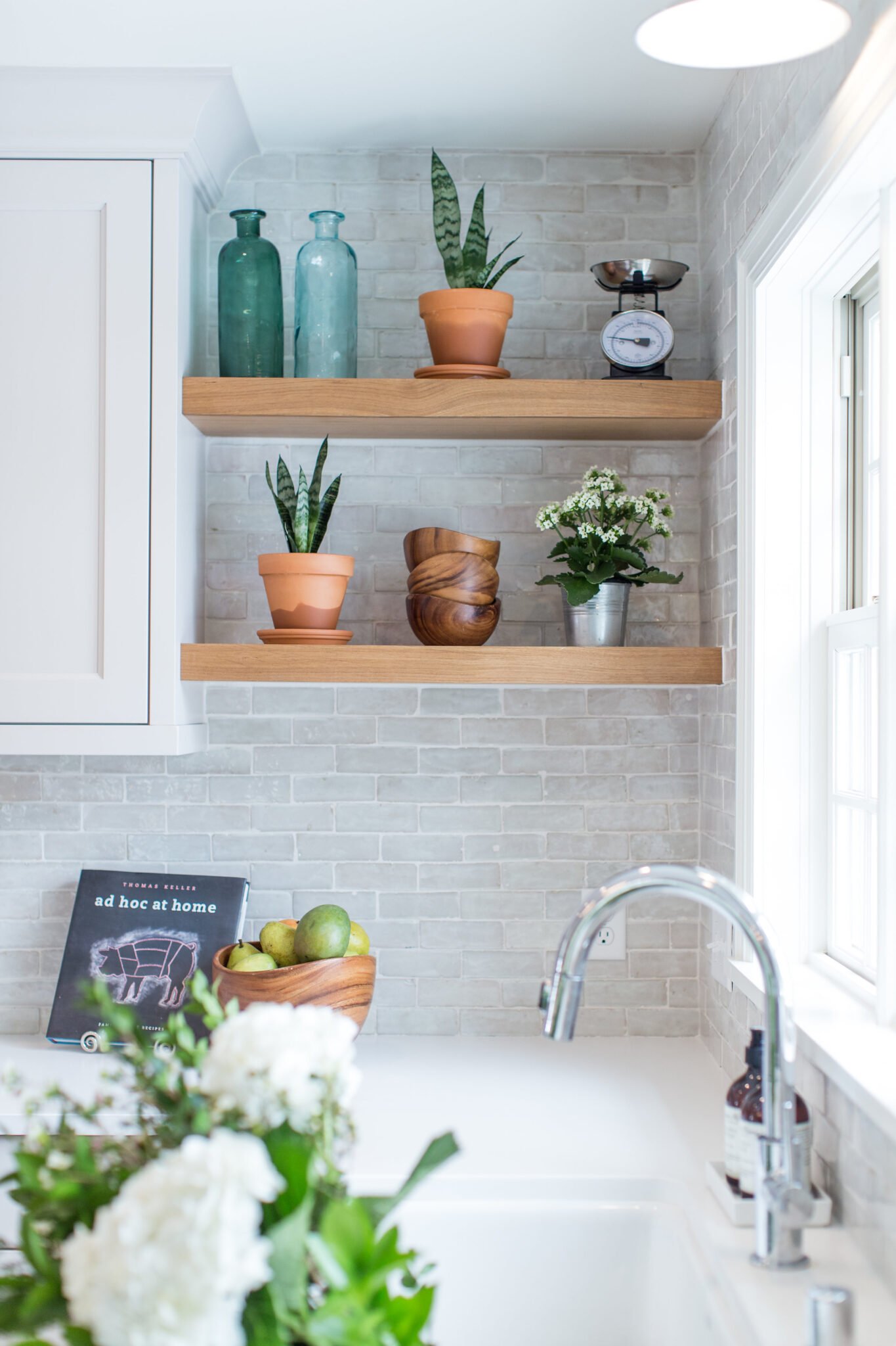 white kitchen with floating shelves and plants in terra cot pots
