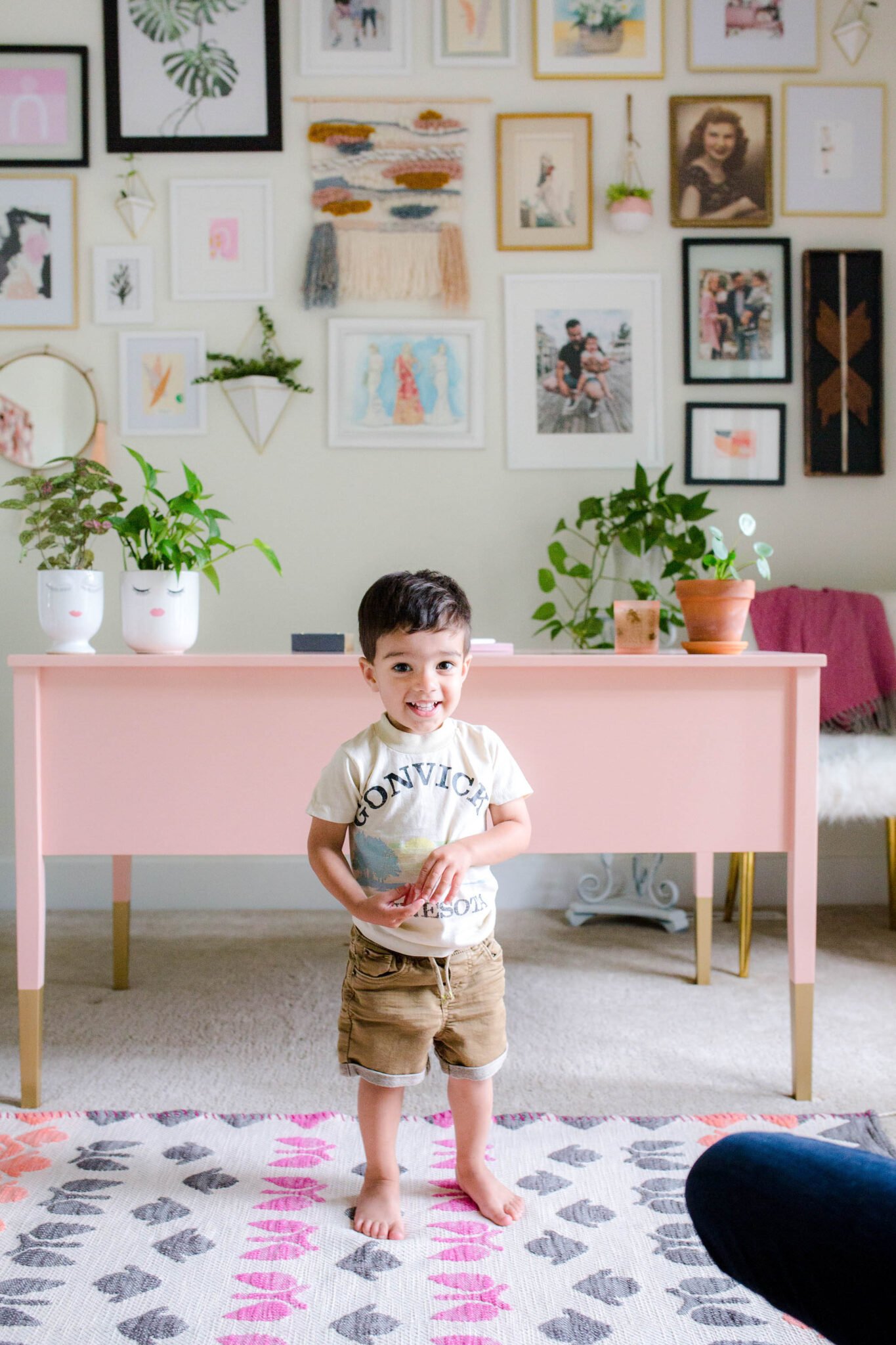 Small child standing in front of pink desk