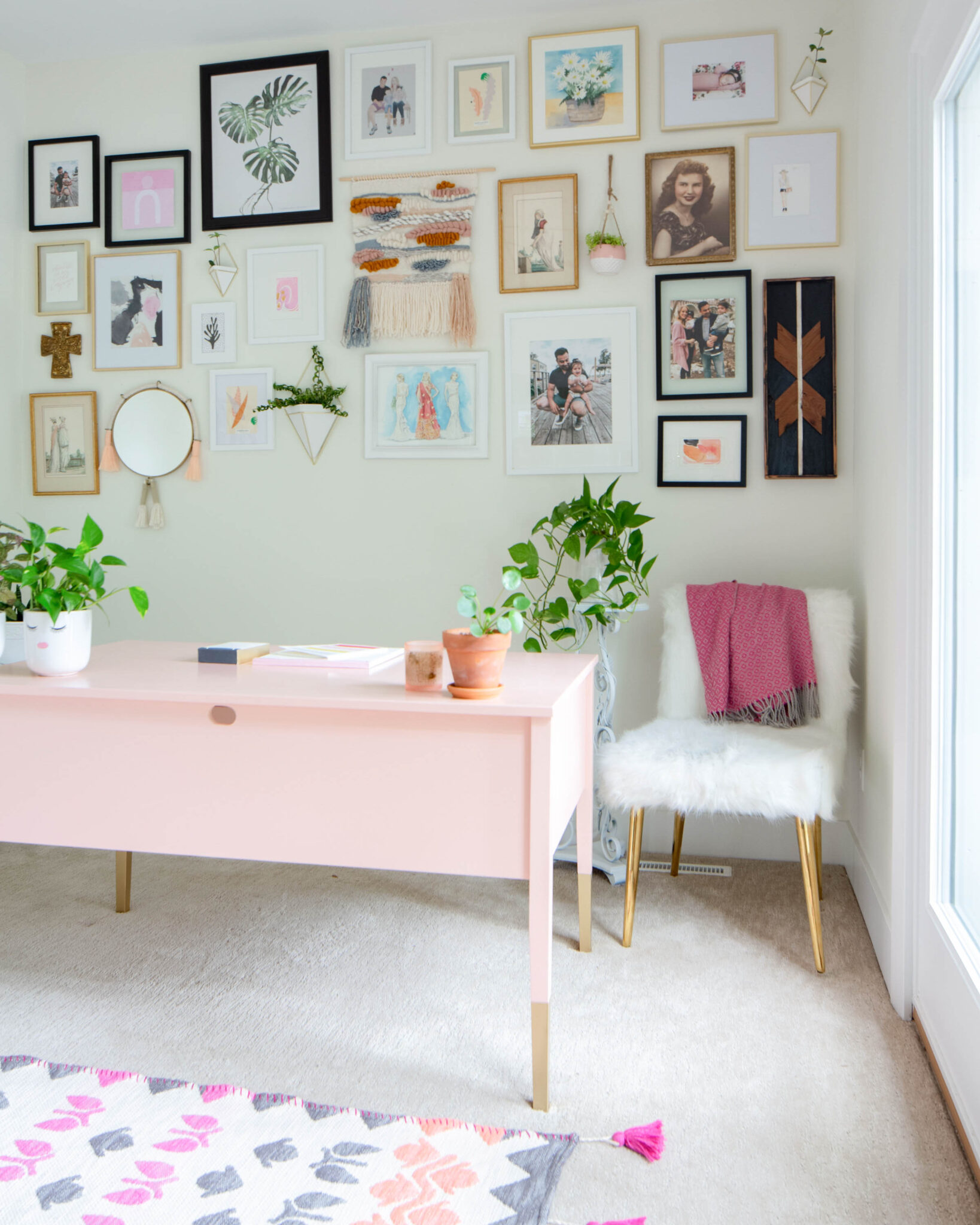Home office with pink desk, furry chair and gallery wall