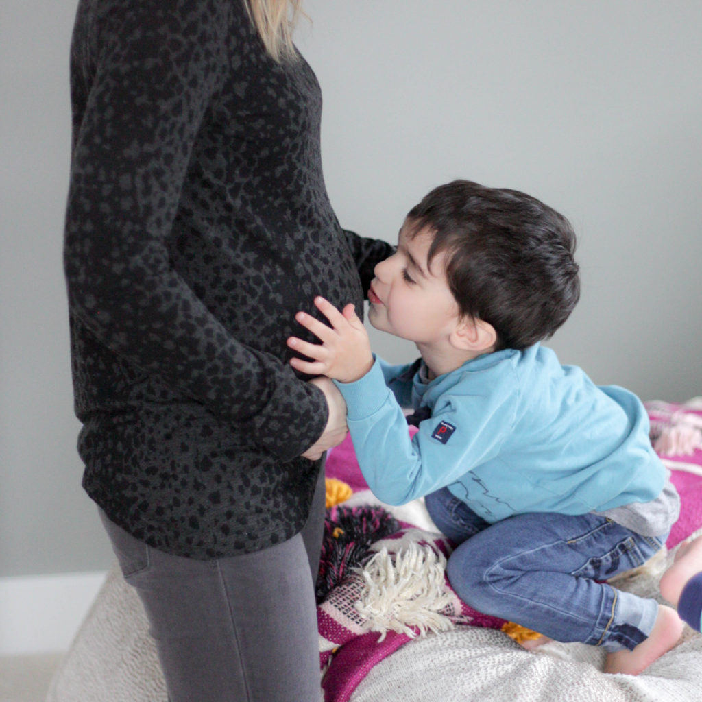 Boy kissing mom's pregnant belly