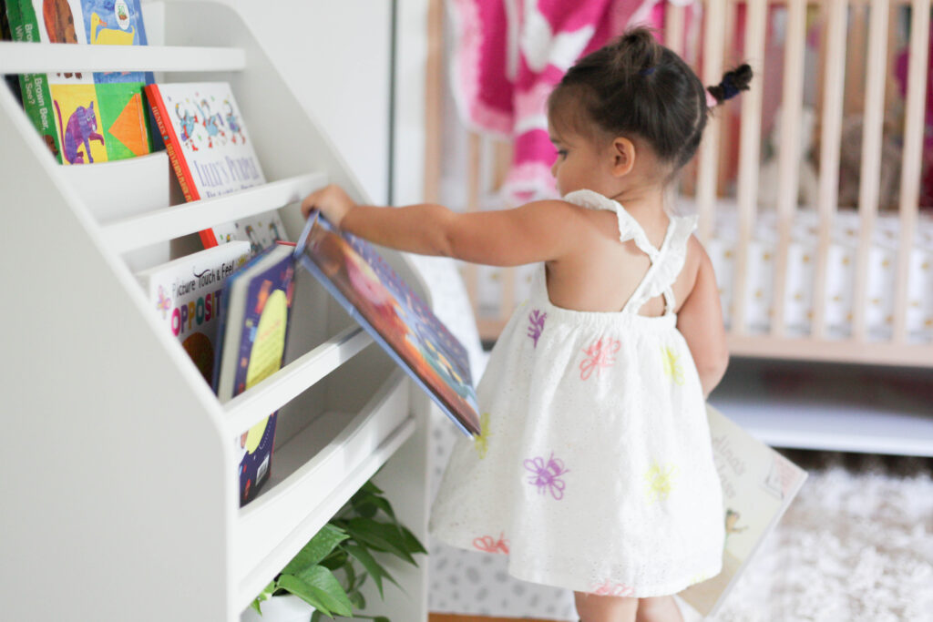 Toddler choosing books from freestanding bookshelf