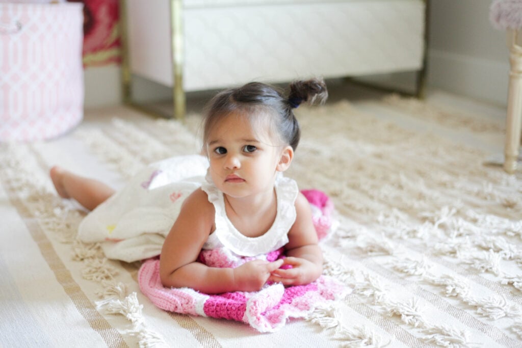 Toddler girl lying on light rug