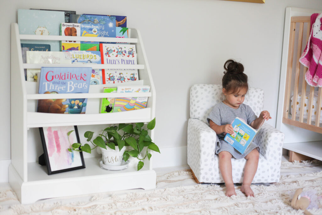 Toddler in toddler-sized armchair reading books