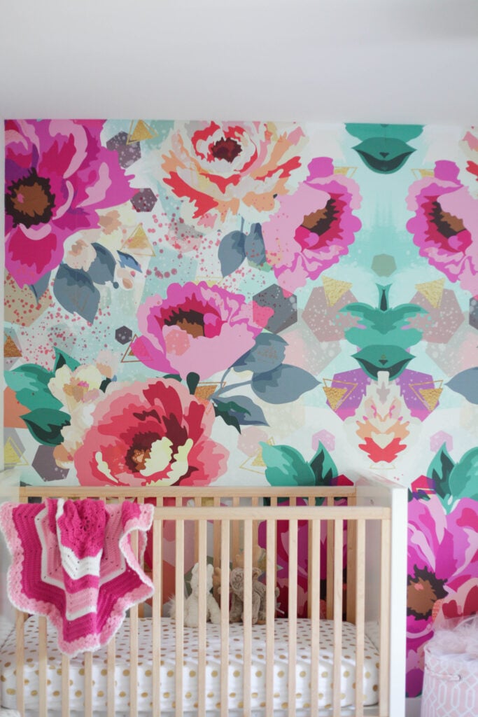 Nursery with one wall of big florals and geometric shapes wallpaper