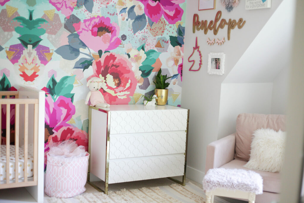 Toddler room with chair, dresser, crib and bright floral wallpaper