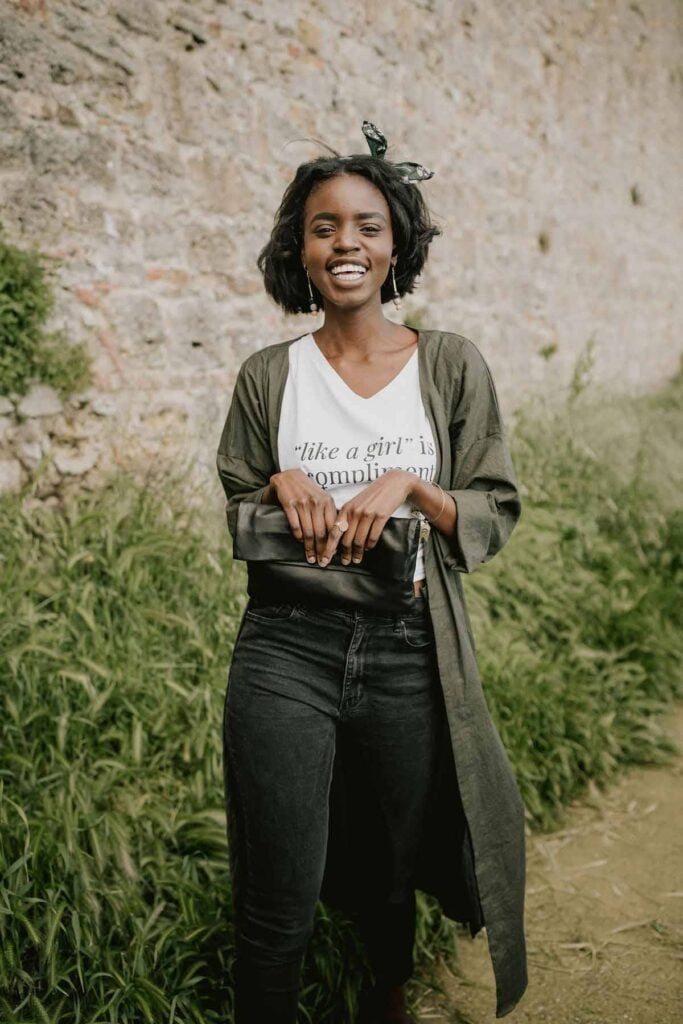 Woman wearing open front duster with black jeans, white graphic tee and clutch