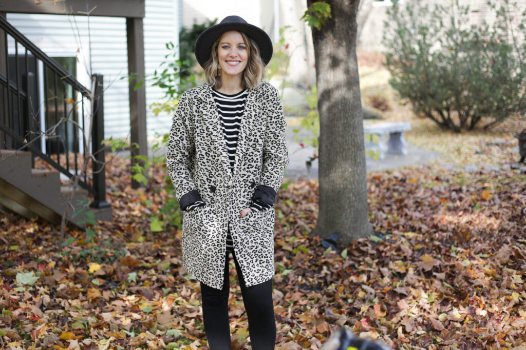 Woman wearing leopard jacket over striped shirt with hat