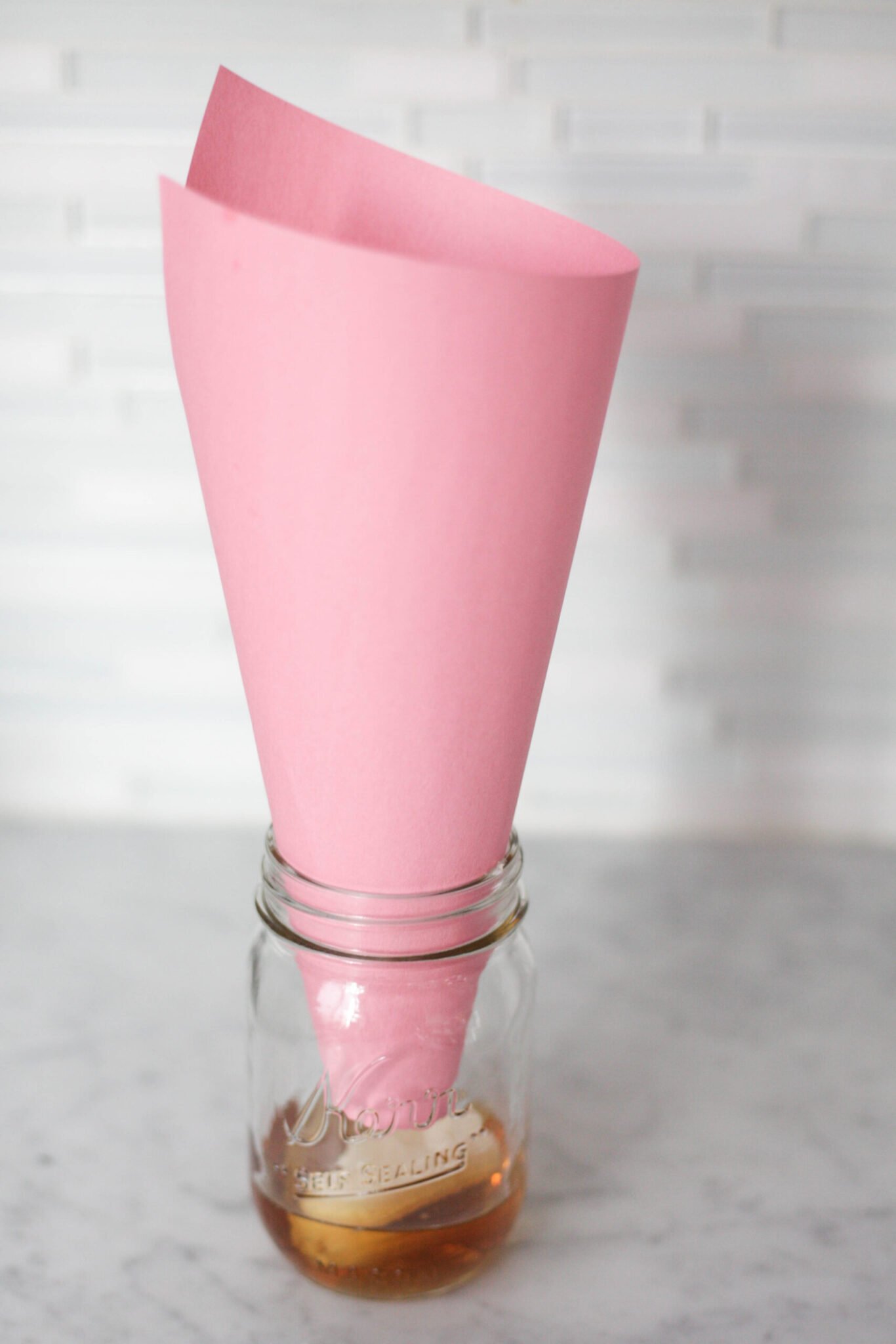 A paper cone to trap fruit flies in a jar with vinegar and a chunk of ripe fruit.