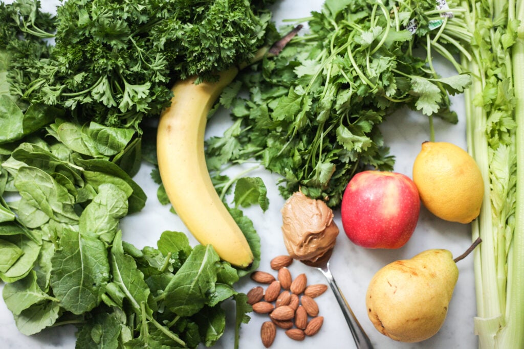 Green smoothie ingredients - leafy greens, banana, apples, pear, lemon and peanut butter