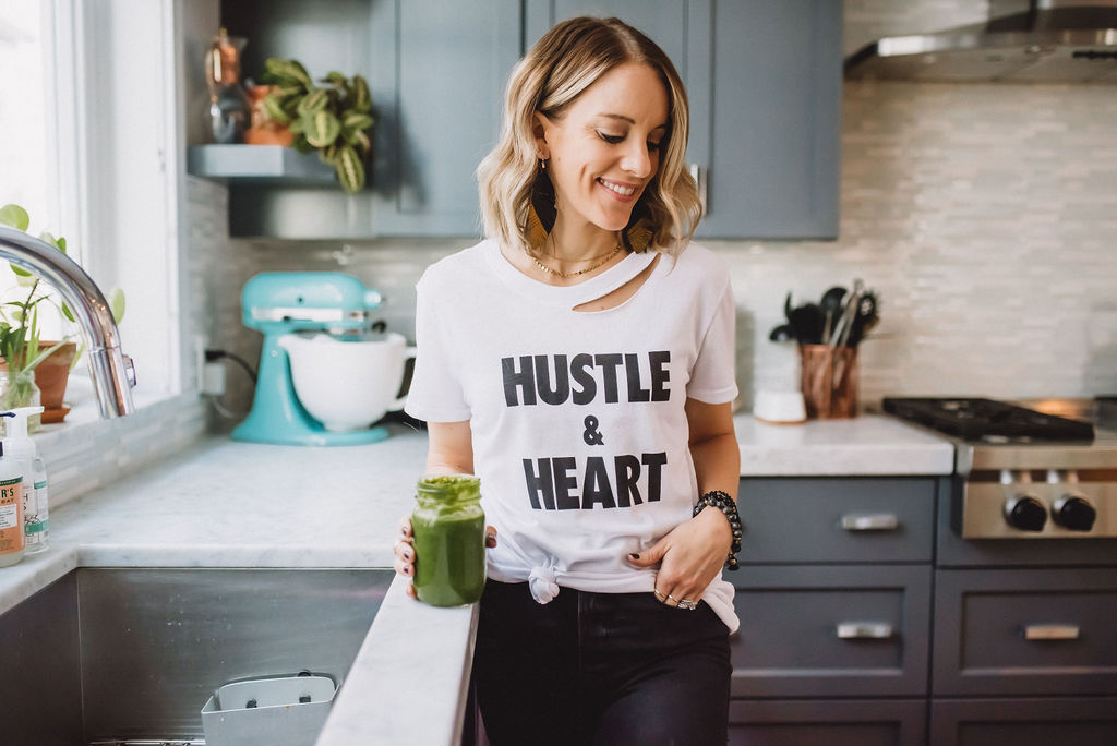 Drinking a green smoothie in a "hustle & heart" tee.