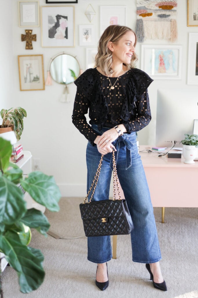 woman in paperbag jeans and black lace top carrying chanel bag