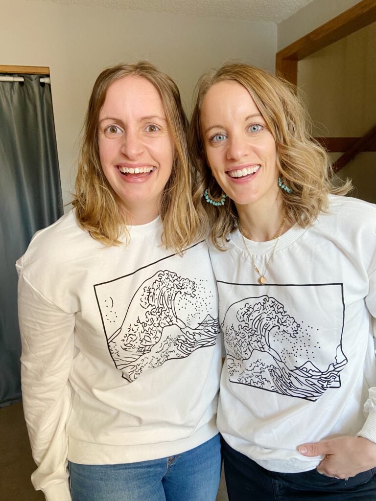 Two women wearing white sweatshirt with wave on it