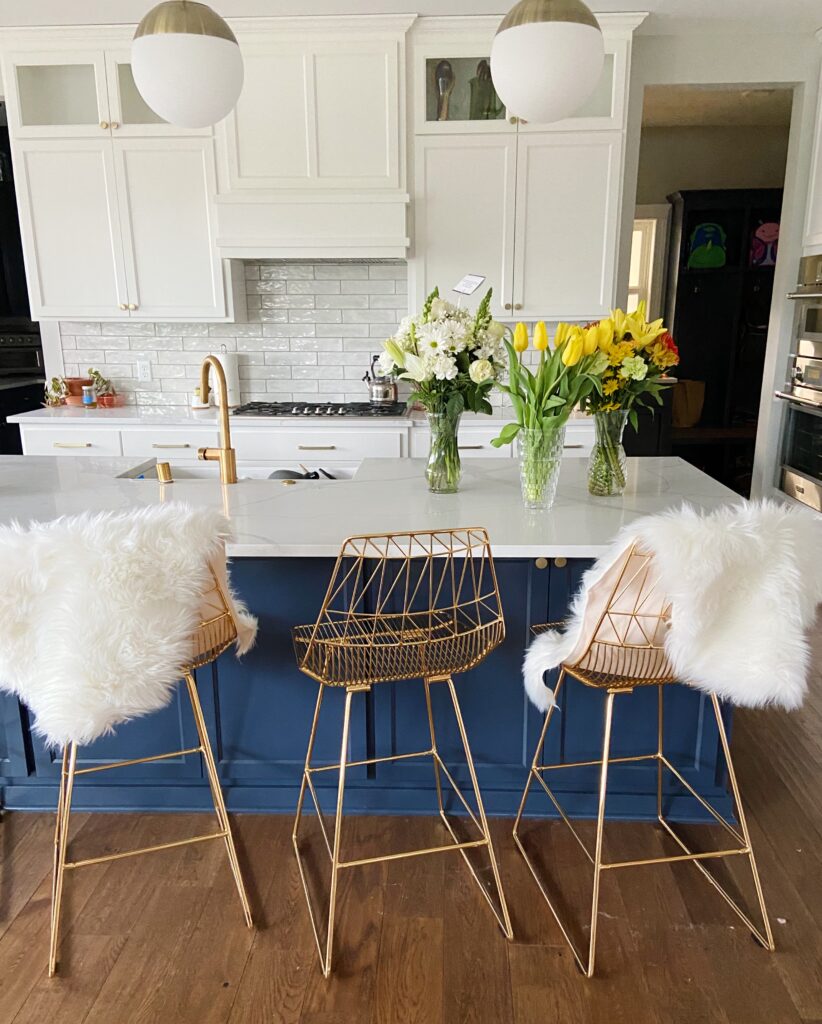 Kitchen with faux sheepskin rugs over barstool chairs