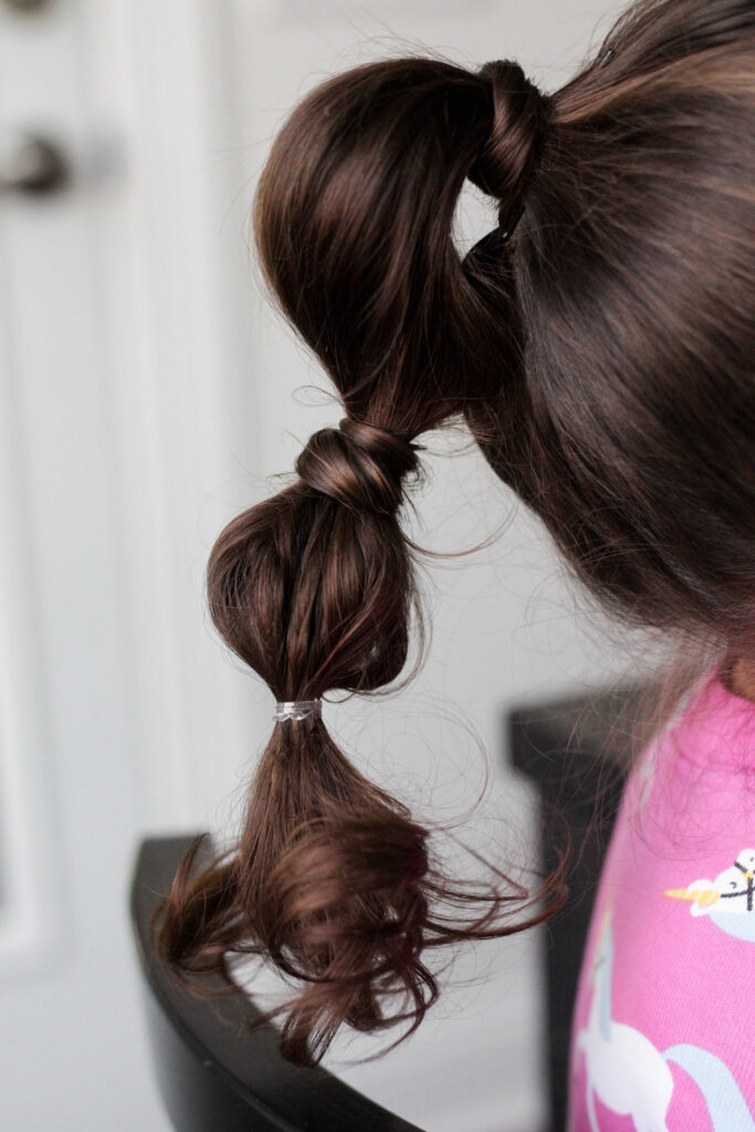 3 elastic wraps in a girls hair creating a bubble pontyail