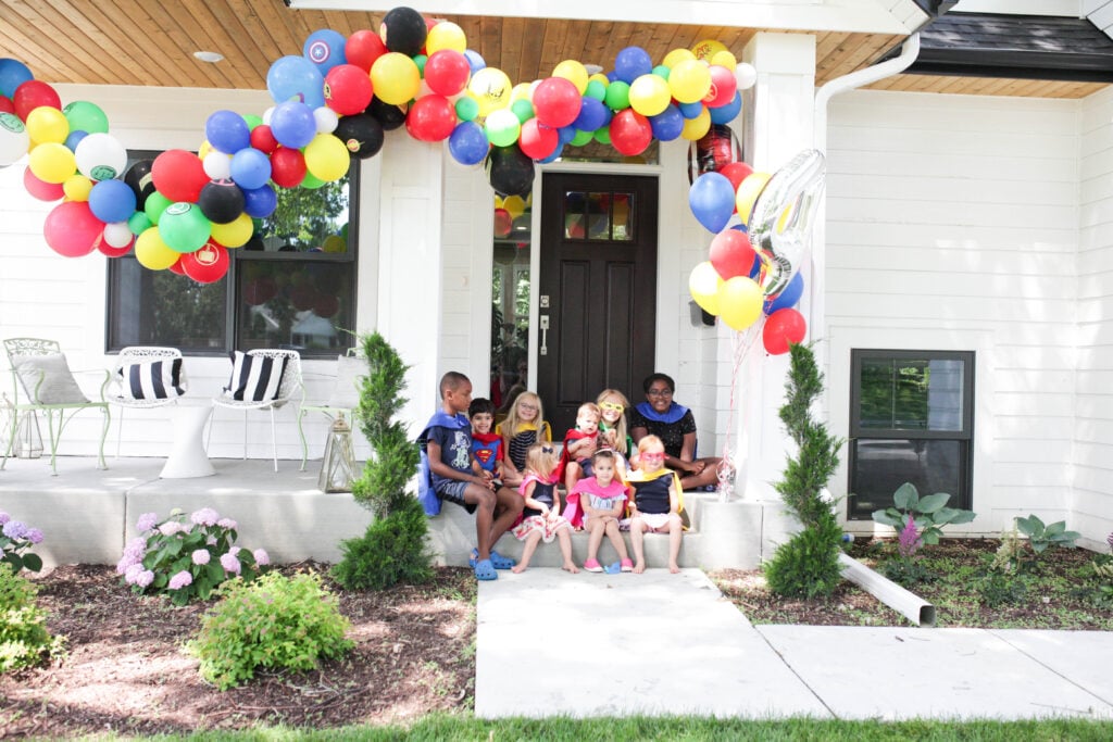 Superhero balloon garland with kids on front step