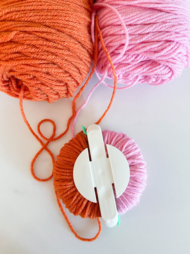 Orange and pink yarn on pom pom maker