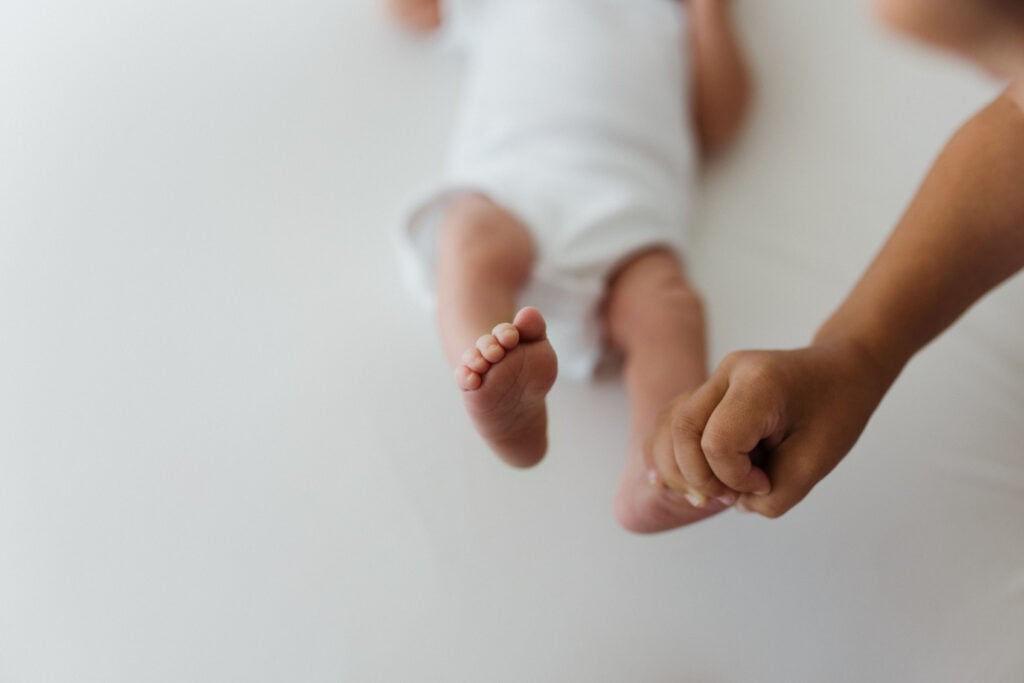 Newborn feet and sibling hand