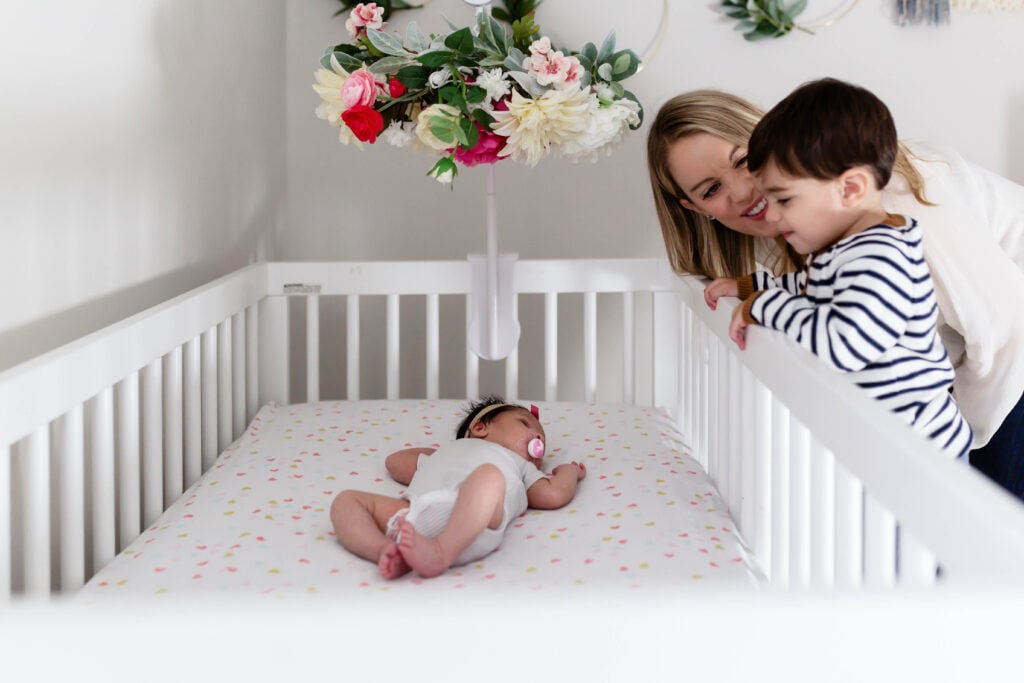 Newborn in crib with mom and brother looking on