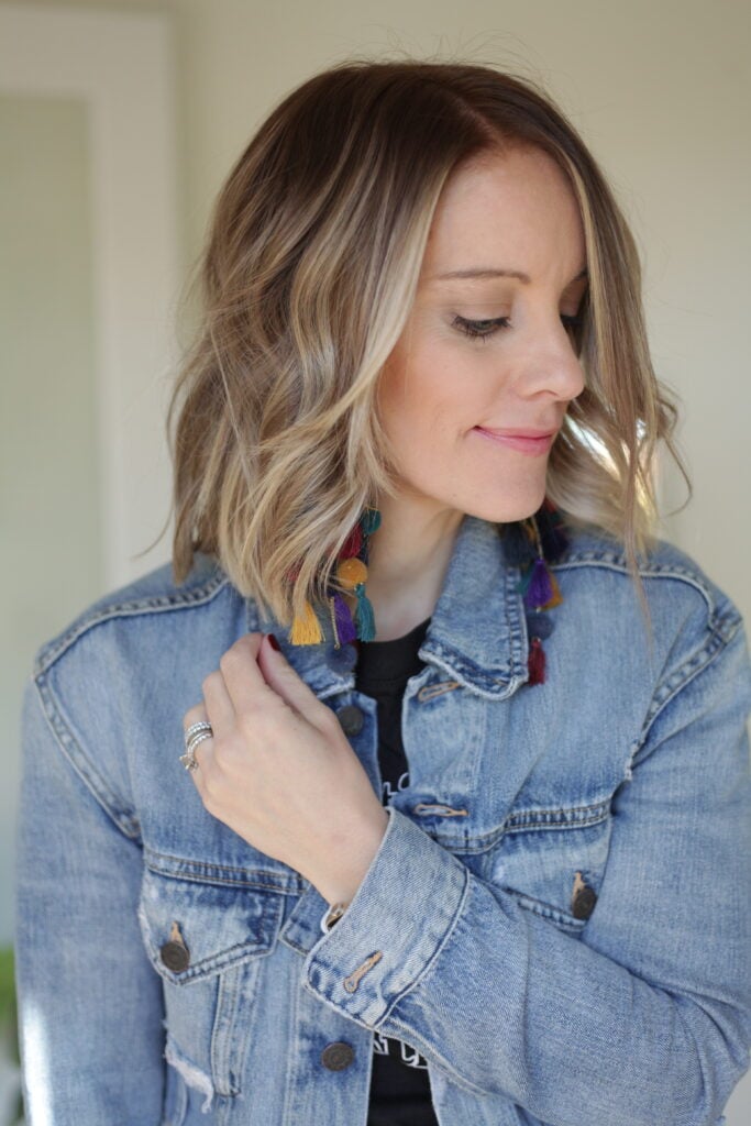 Woman with short blonde hair, tassle earrings and jean jackets