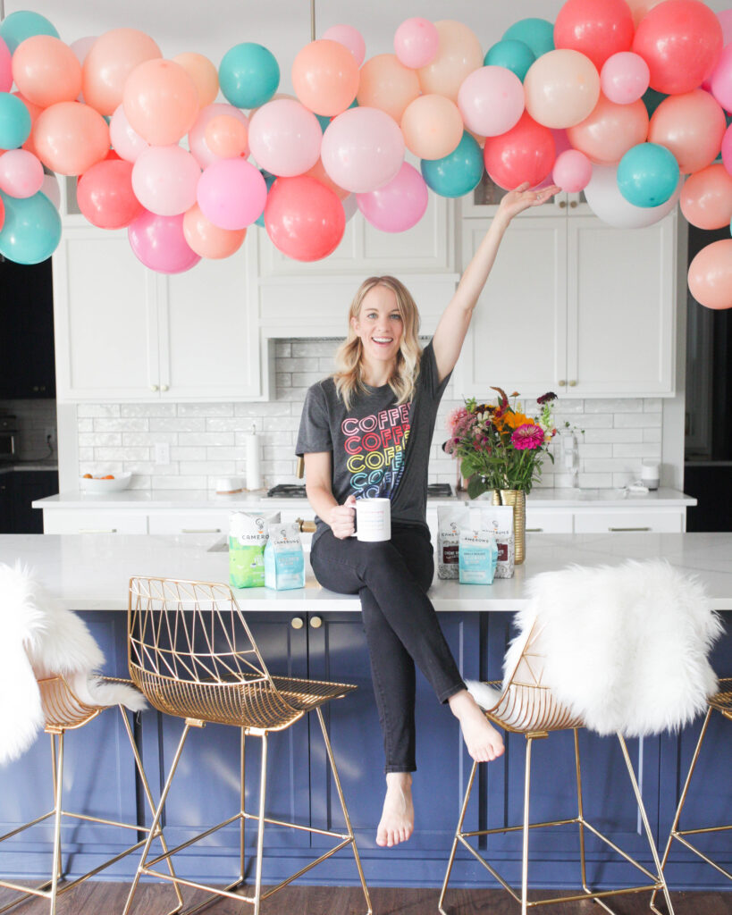 Woman on kitchen island under pink, coral and teal balloon garland