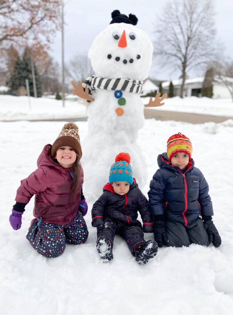 3 kids in front of a snowman