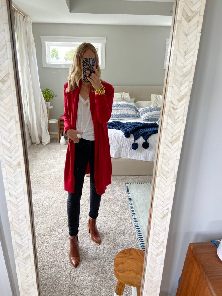 Woman in white tee, black jeans, long red cardigan and boots