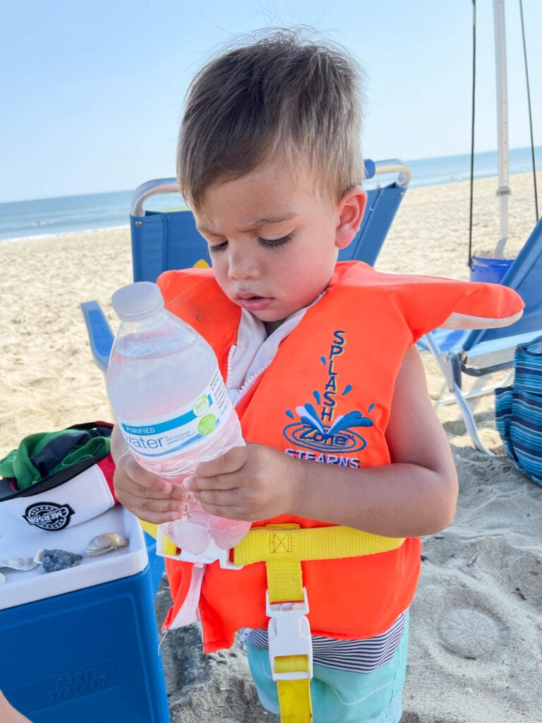 baby with water bottle on the beach