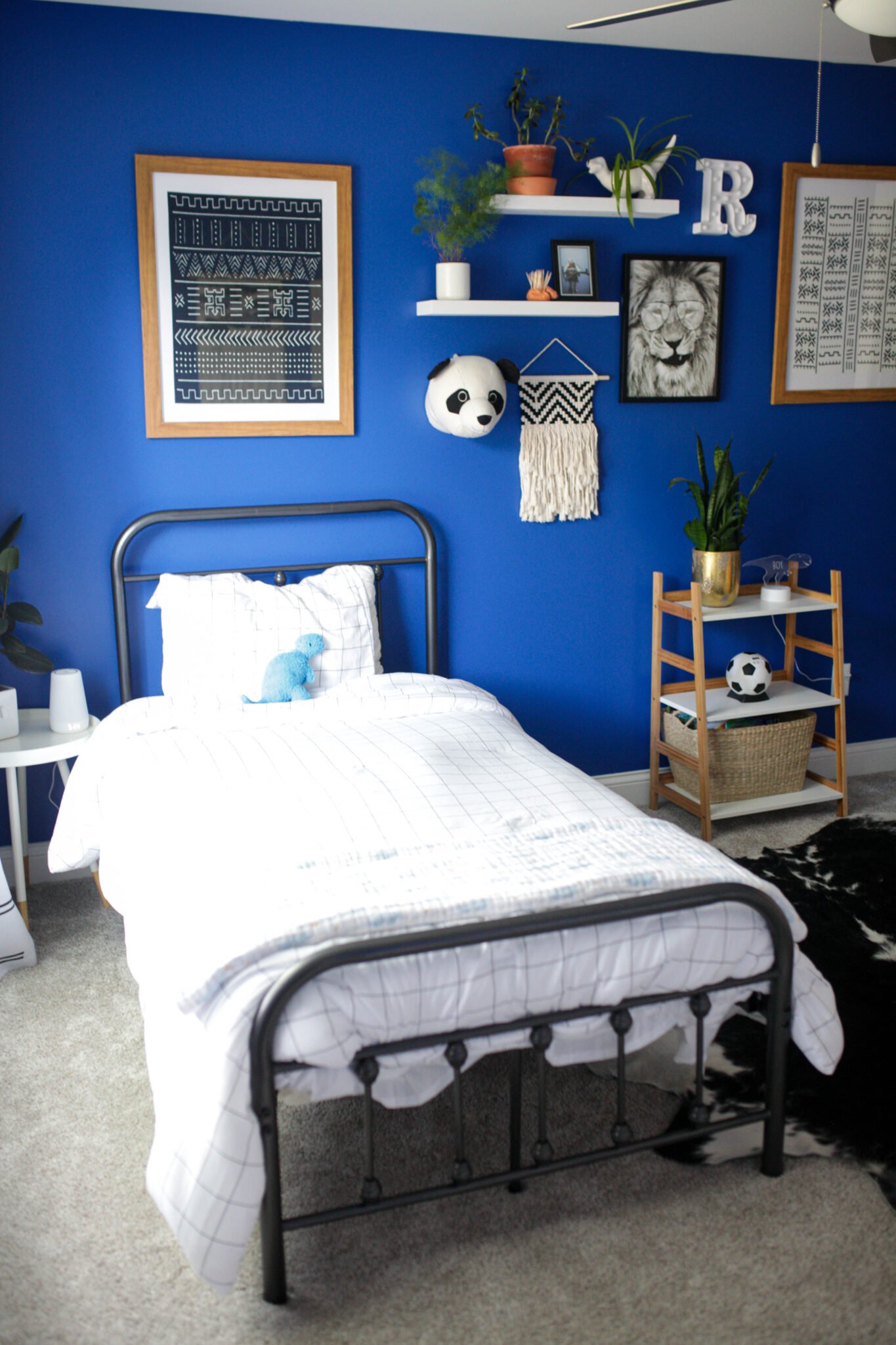 Bed and gallery wall in bright blue boys bedroom