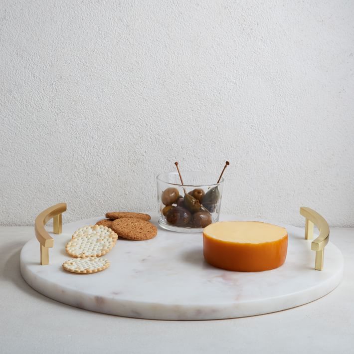 Circular marble tray with brass handles with cheese and crackers