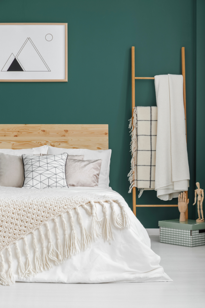 Boho bedroom with green wall and light floors and bedding