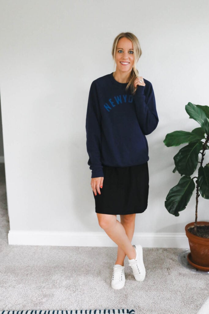 woman wearing a shift dress with a sweatshirt over the top and white sneakers