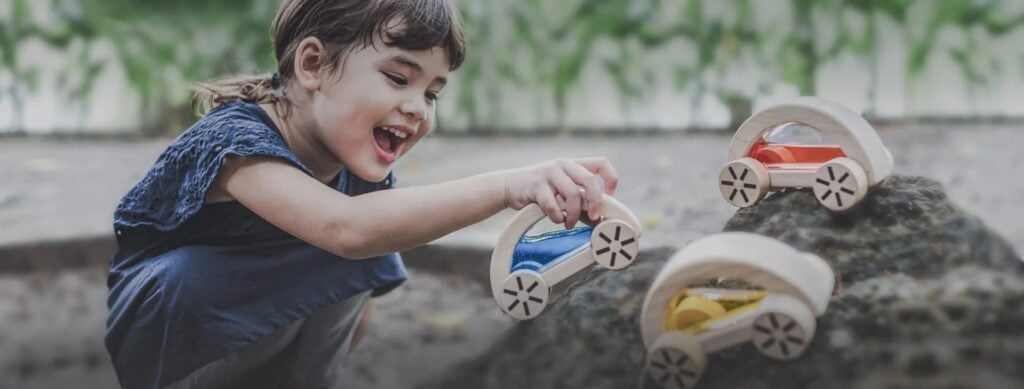 Girl playing with wooden car toys