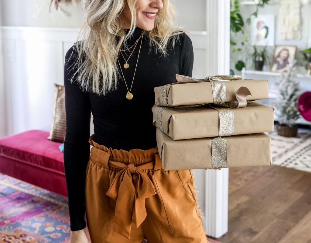 woman in stack of necklaces holding gifts