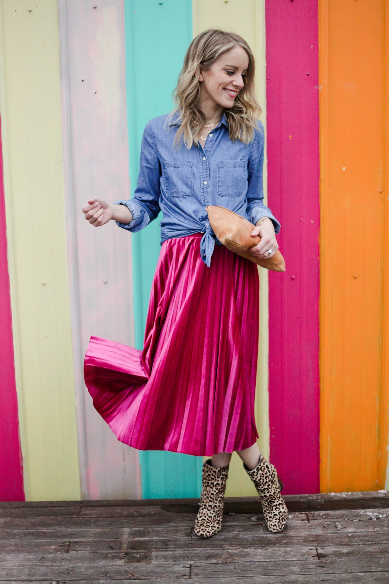 woman wearing pink pleated skirt, chambray top and leopard boots