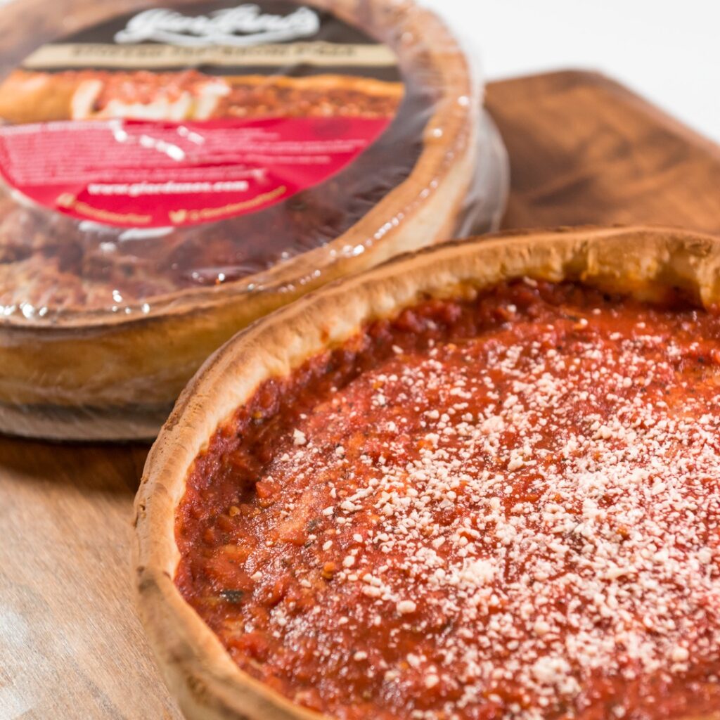 Two deep-dish pizzas - one wrapped in plastic
