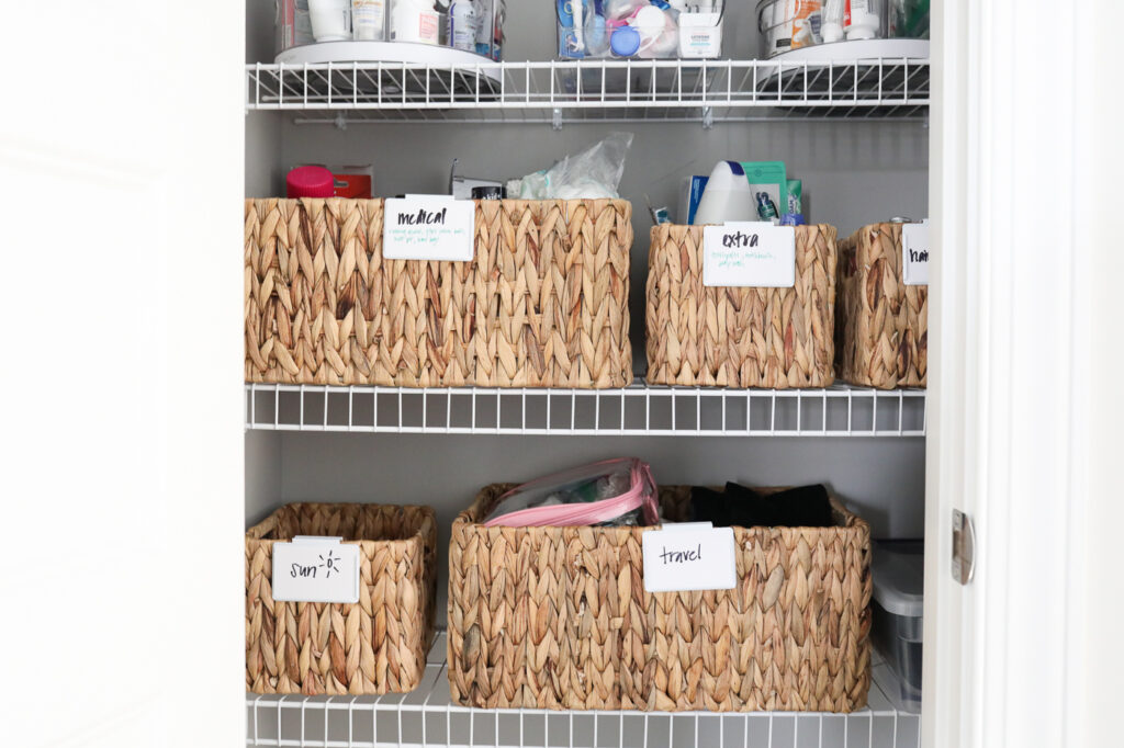 organized linen closet baskets with labels