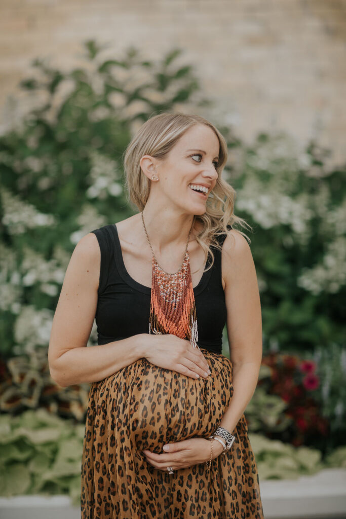 pregnant woman holding belly in leopard skirt and black top