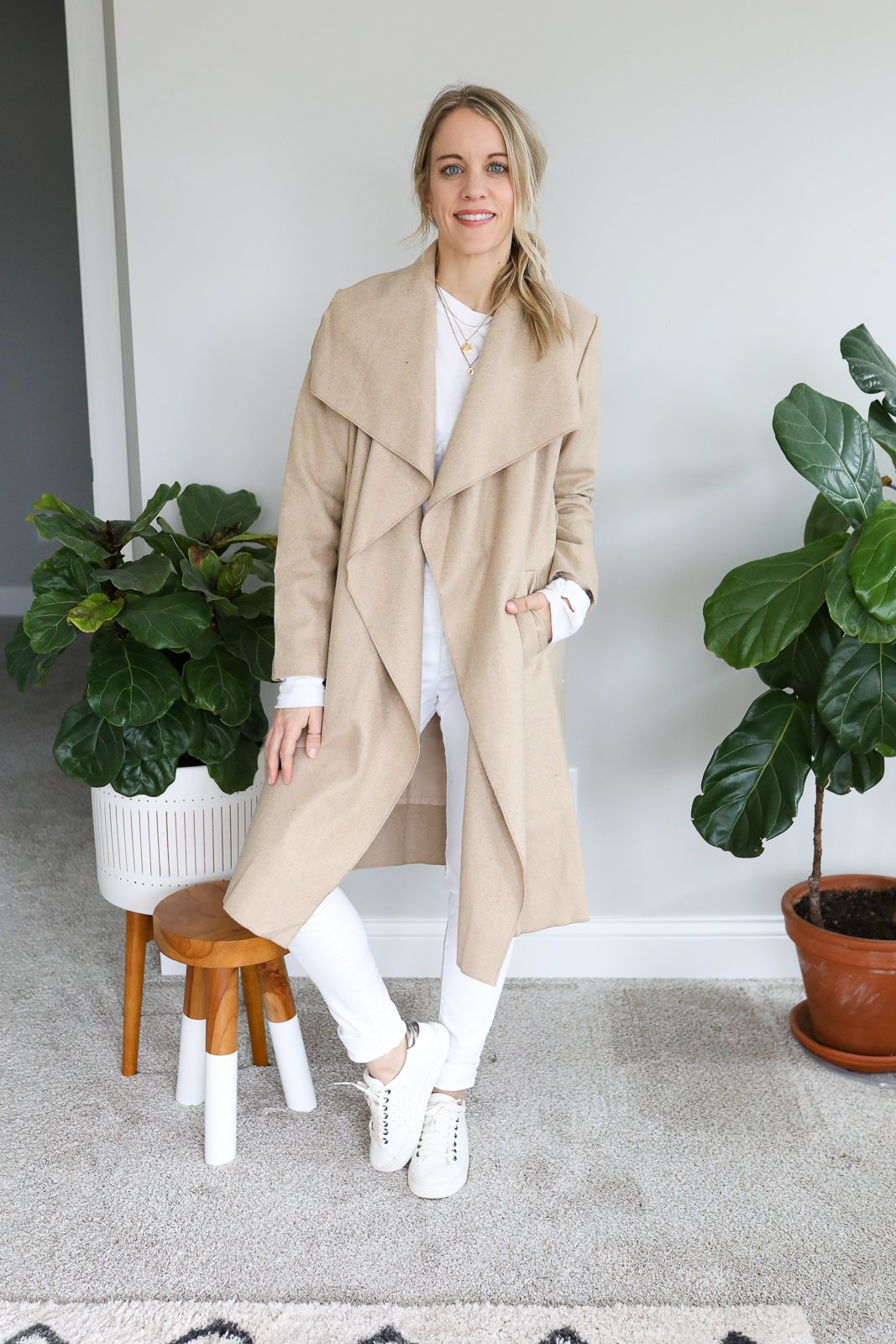 woman wearing white jeans and long tan coat