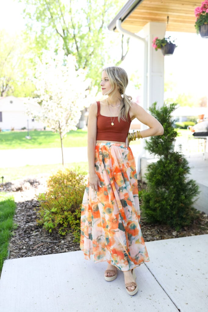 Woman wearing orange maxi skirt and cropped top and heels with gold jewelry