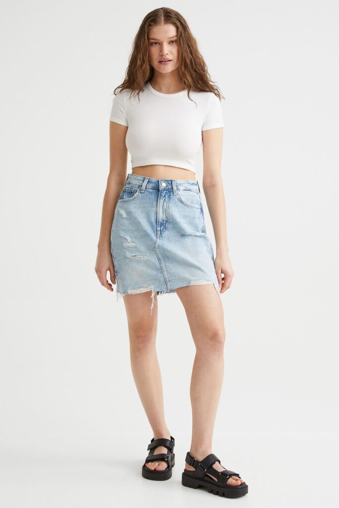 Woman wearing denim skirt, black sandals and white top