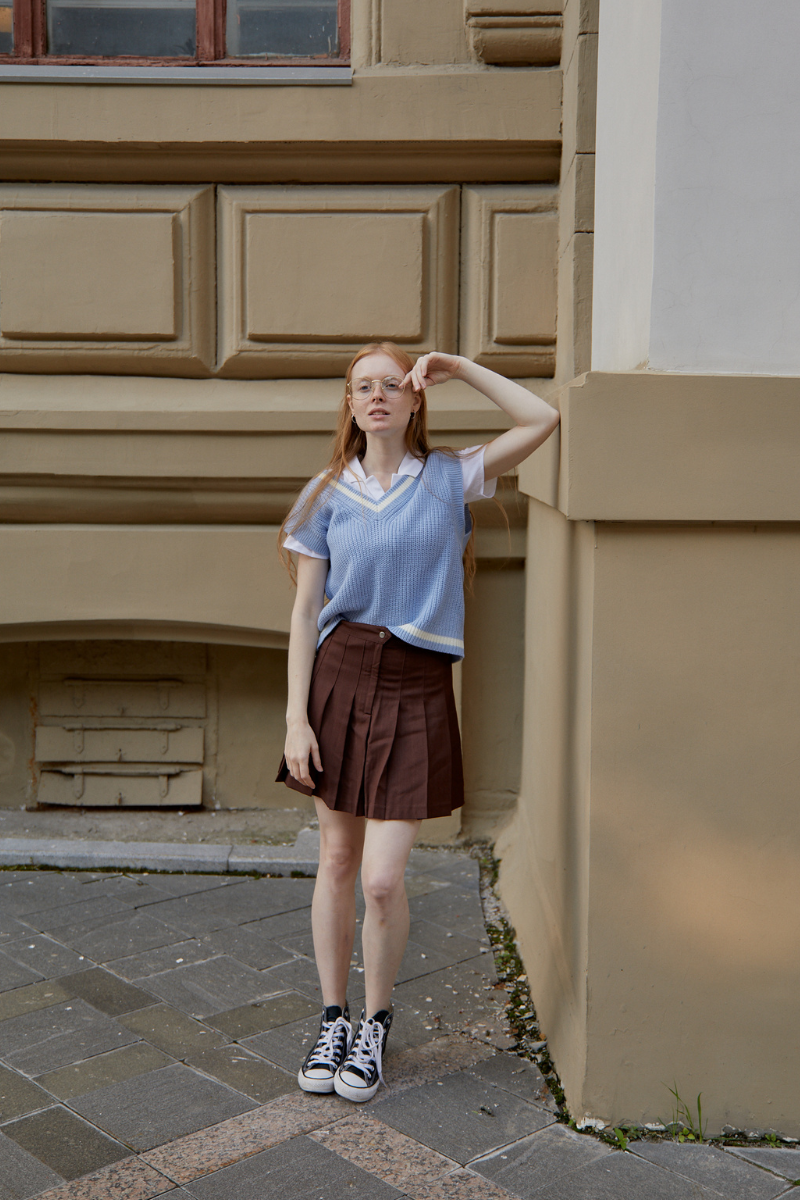 woman leaning against wall wearing box pleat skirt