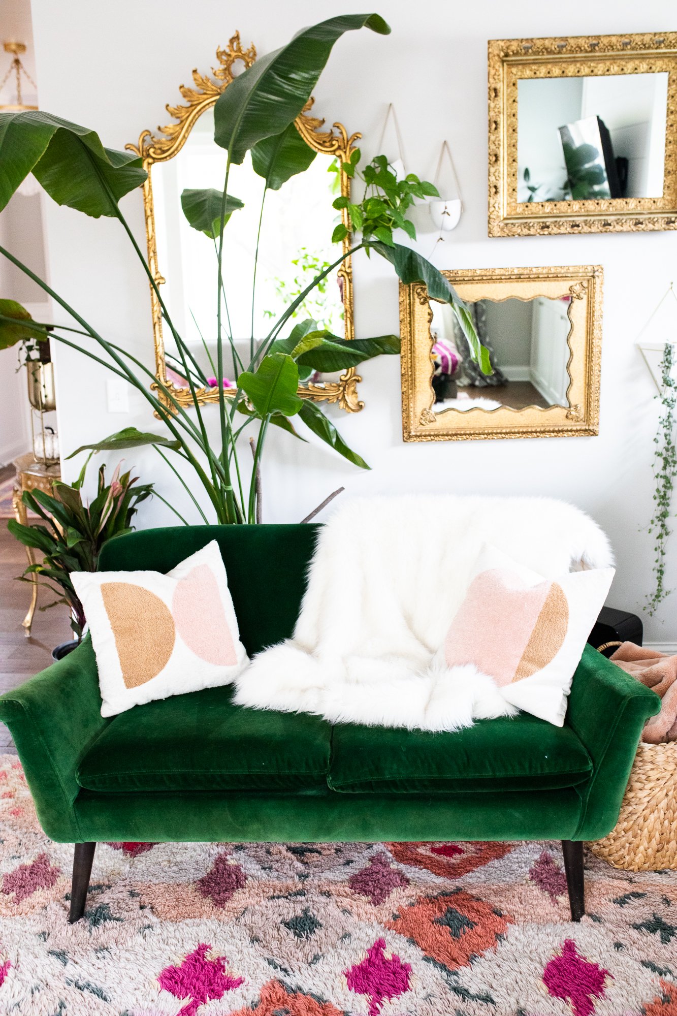 living room with green love seat, furry blankets and gold mirrors