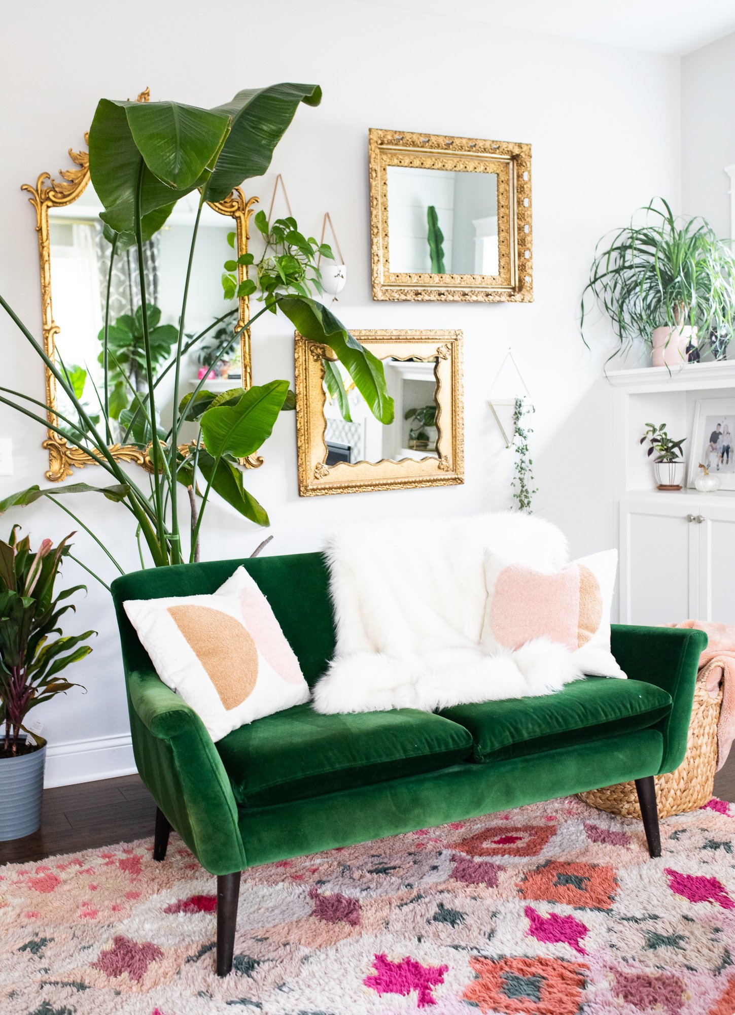 living room with green love seat, furry blankets and gold mirrors and colorful rug