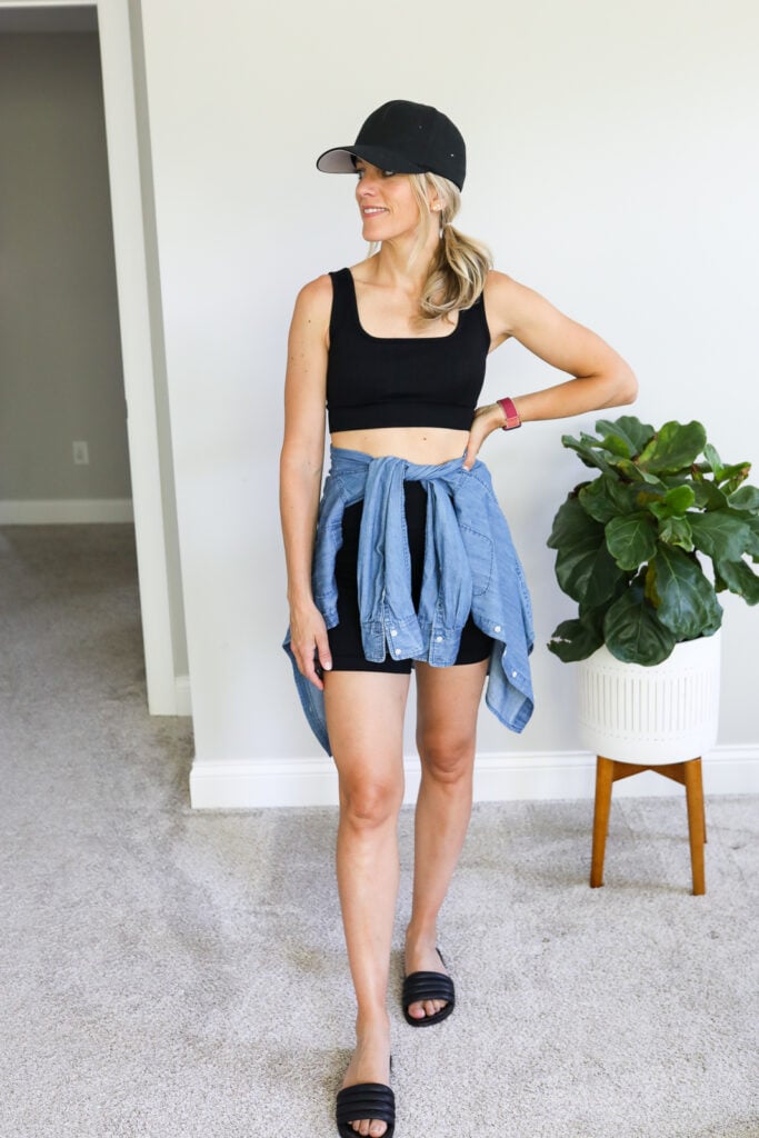 woman wearing bike shorts, sports bra, chambray shirt and baseball cap