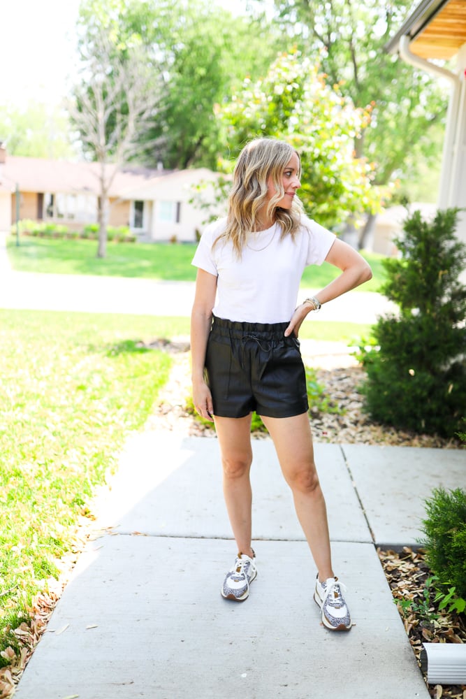 woman wearing faux leather shorts and white tshirt with statement sneakers