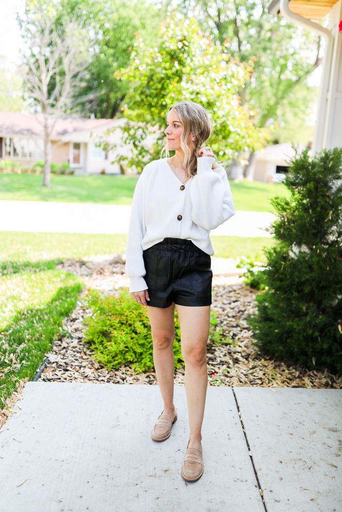 woman wearing faux leather shorts and white cardigan