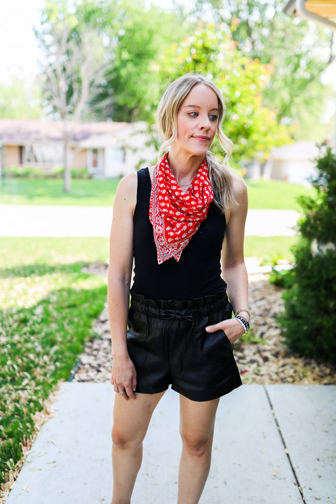woman wearing faux leather shorts black bodysuit and red bandana